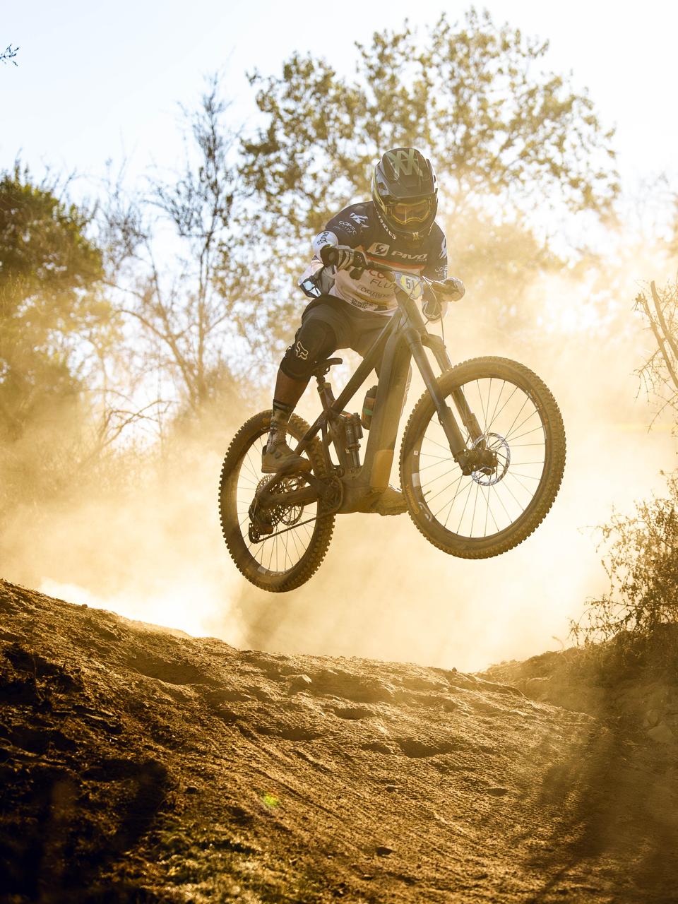 Santiago jumping his mountain bike on a dusty trail